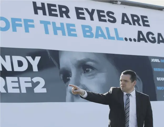  ??  ?? 0 Scottish Conservati­ve party leader Douglas Ross stands in front of a picture of First Minister Nicola Sturgeon as he launches an ad van campaign in Glasgow