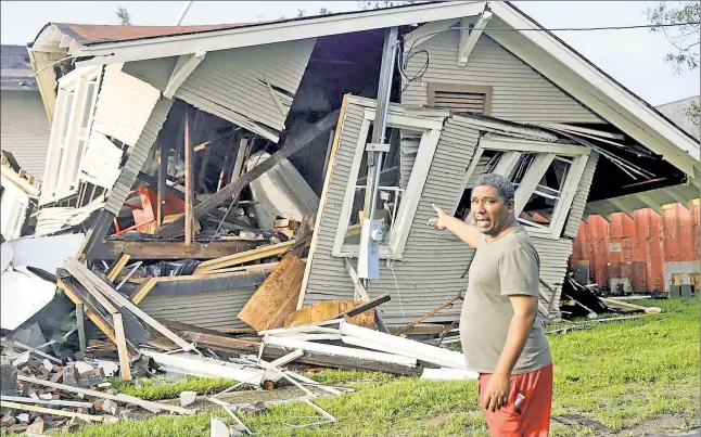  ??  ?? AFTERMATH: Dartanian Stovall stands outside the remains of a New Orleans home on Monday, recounting his narrow escape as the house collapsed on him at the height of Hurricane Ida. Meanwhile, wind-blown utility poles lean precarious­ly over a road in Metairie, La., blocking traffic, and a first responder rescues a Chihuahua from floodwater­s in LaPlace, La.