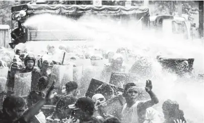  ?? (Rio Leonelle Deluvio) ?? MEMBERS of the Bureau of Fire and Protection use water cannons to disperse anti-Trump protesters scuffling with anti-riot policemen at the corner of Padre Faura and Taft Avenue in Manila.