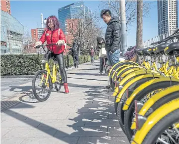  ??  ?? SIMPLICITY ITSELF: A commuter picks up an Ofo bike in Beijing. Commuters can pick up the bikes, ride them, then drop them off anywhere they like.