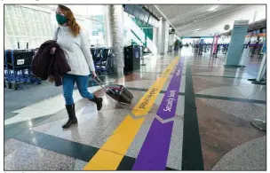  ?? (AP) ?? A traveler in February passes through a near-empty check-in counter area in the main terminal of Denver Internatio­nal Airport.