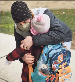  ??  ?? Daniel Barreira hugs daughter Cadence, 6, as he drops her off for a return to school after two months of remote home instructio­n at Long Hill Elementary School in Shelton on Monday.