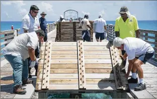  ?? ANDRES LEIVA / THE PALM BEACH POST ?? A City of Lake Worth grounds crew on Thursday lifts floorboard­s off the Lake Worth Municipal Pier. The pier closed at noon on Thursday, and will remain closed until sometime after Hurricane Irma passes by.