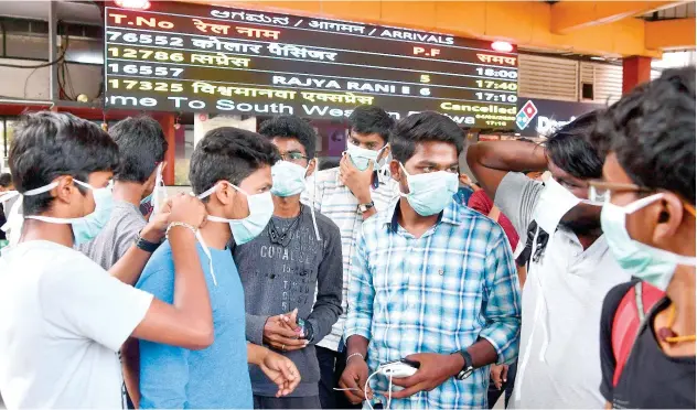  ?? Agence France-presse ?? ↑ Tourists wear face masks as a preventive measure against the spread of coronaviru­s at the Bangalore City Railway Station on Wednesday.