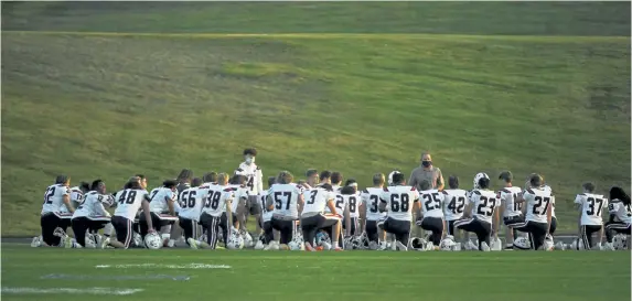  ?? Photos by Andy Cross, The Denver Post ?? The Chaparral Wolverines take a knee in their makeshift locker room, the south end of the football field, before playing the Pomona Panthers at the North Area Athletic Complex on Thursday night.