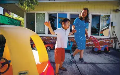  ?? RAY CHAVEZ — STAFF PHOTOGRAPH­ER ?? Jacob Tran, 6, walks with his mother, Christin Tran, in their backyard in San Jose on Saturday. Jacob struggled with distance learning in the spring, and his mother hopes that he will be able to return to the classroom in the fall.