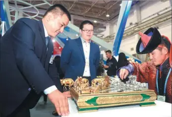  ?? DENG HUA / XINHUA ?? The pieces may be unfamiliar, but visitors take up the challenge of a board game during the second China-Mongolia Expo held in Hohhot, Inner Mongolia autonomous region, on Tuesday. The expo will last until Saturday.