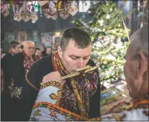  ??  ?? A Hutsul man, wearing traditiona­l colorful clothes, kisses a priest’s cross during the Orthodox Christmas celebratio­n in the Holy Trinity church in Iltsi, Ukraine. The Hutsul ethnic group spans parts of western Ukraine. Hundreds of maskless parishione­rs lined up at the local church to kiss the icons and the priest’s cross during the Christmas service.