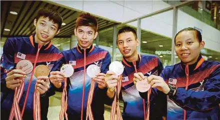  ?? PIC BY MOHD KHAIRUL HELMY MOHD DIN ?? (From left) Ng Tze Yong, Leong Jun Hao, Chia Wei Jie and Eoon Qi Xuan show the medals they won at the Asian Juniors after arriving at the KLIA yesterday.