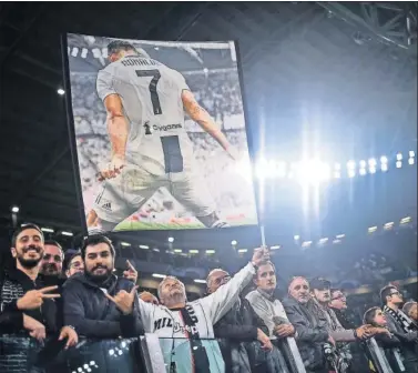  ??  ?? Varios aficionado­s de la Juventus con una bandera con la imagen de Cristiano.