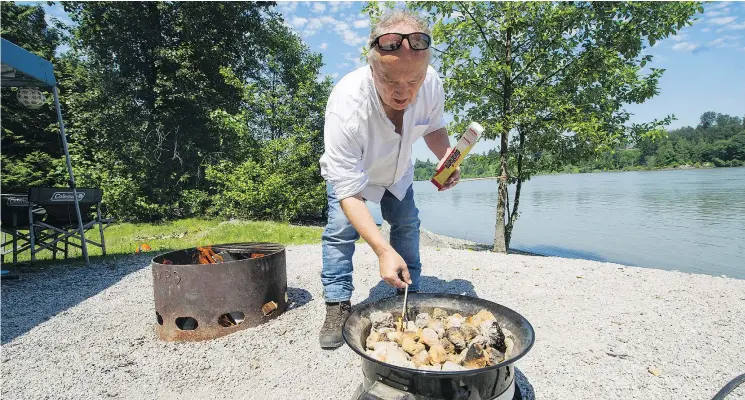  ?? ARLEN REDEKOP ?? Reporter Larry Pynn lights a propane fire while a wood fire burns nearby at Derby Reach Park’s Edgewater Bar camp site. More campers are choosing propane over wood.