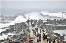  ?? AFP ?? People walk along a breakwater at Kasimedu fishing harbour as Cyclone Phethai approaches Chennai on Sunday.