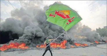  ?? AFP ?? A protester waves an Iraqi Hezbollah flag during a demonstrat­ion against state corruption and unemployme­nt in the capital Baghdad. ■