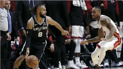  ??  ?? San Antonio Spurs guard Patty Mills (8) controls the ball as Miami Heat forward Rodney McGruder defends during the first half of an NBA basketball game, on Wednesday, in Miami. AP PHOTO/LYNNE SLADKY