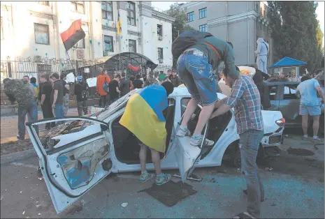  ?? SERGEI CHUZAVKOV/AP PHOTO ?? Ukrainian protesters destroy cars Saturday near the Russian Embassy during a rally in Kiev. About 100 protesters hurled eggs and paint at the embassy and overturned several parked cars with diplomatic plates. The Ukrainians were protesting an attack on...