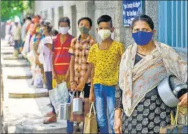  ?? PTI ?? People wait for free cooked meals at a distributi­on centre in New Delhi on Thursday.