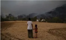  ?? Photograph: Yasin Akgül/AFP/Getty Images ?? A woman and a girl hold hands while watching wildfires burning in Köyceğiz district in Turkey in 2021.