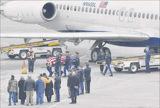  ?? Lori Van Buren / Times Union ?? Relatives look on as the remains of Pfc. John Martin, who vanished in North Korea in late 1950, are removed from a Delta airplane at the Albany Internatio­nal Airport on Friday in Colonie. His great-great nephew, Airman 1st Class Schuyler Dolton, is seen saluting at far right.