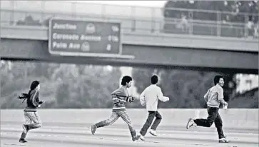  ?? Photograph­s by Don Bartletti Los Angeles Times ?? A GROUP OF immigrants sprints across Interstate 5 in San Ysidro in 1990, their clothes damp from the nearby Tijuana River valley. The San Diego area was once the busiest sector for illegal immigratio­n in the U.S.