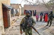  ?? (AFP) ?? A member of Syrian Kurdish Asayish security forces walks past a house during a raid against IS group fighters in Raqa, on January 29