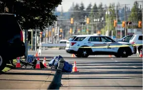  ?? AP ?? A bike and person’s belongings are seen on the sidewalk behind police tape at the scene of a shooting in Langley, British Columbia.