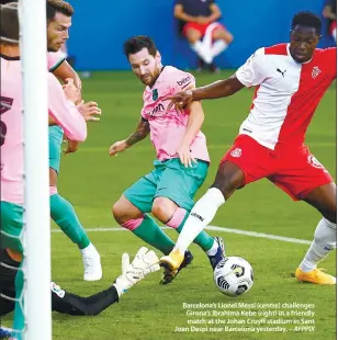  ??  ?? Barcelona’s Lionel Messi (centre) challenges Girona’s Ibrahima Kebe (right) in a friendly match at the Johan Cruyff stadium in Sant Joan Despi near Barcelona yesterday. – AFPPIX