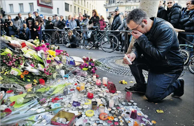  ?? — GETTY IMAGES ?? People gather to lay flowers and light candles at La Belle Équipe restaurant in the wake of Friday’s terrorist attacks in Paris.