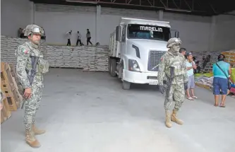  ??  ?? Elementos de la Marina vigilaron ayer la entrega a campesinos de costales de fertilizan­te en una bodega de la colonia Moctezuma, en la zona rural de Acapulco.