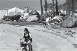  ?? GENARO MOLINA/LOS ANGELES TIMES ?? A bicyclist rides past several tents pitched by homeless residents along the bike path in Venice, California, on April 16.