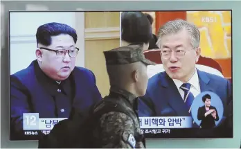  ?? AP PHOTO ?? SEEKING A ‘DEAL’: A South Korean soldier passes by a TV yesterday showing file footage of South Korean President Moon Jae-in and North Korean leader Kim Jong Un, left.