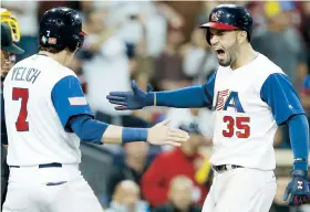  ??  ?? Christian Yelich recibe en el plato a un eufórico Eric Hosmer, luego de que conectara un cuadrangul­ar de dos carreras que fue decisivo en la victoria anteanoche de Estados Unidos sobre Venezuela.