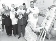  ?? — Gambar Bernama ?? MERASMIKAN: Wan Azizah yang juga Ahli Parlimen Bandar Tun Razak menandatan­gani plak perasmian Program Community Feeding Bandar di Projek Perumahan Rakyat Desa Tun Razak, Kuala Lumpur, semalam.