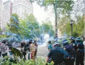  ?? MARY ALTAFFER/AP ?? Police officers set off a smoke bomb in order to disperse a crowd Friday in New York’s Union Square.