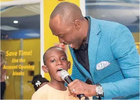  ??  ?? Contribute­d This little boy passionate­ly sings along with Kevin Downswell as the gospel artiste and JN Group Brand Ambassador, gets patrons at the Half Way-Tree branch of the JN Bank in a worship mood during Customer Appreciati­on Day activities.