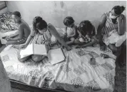  ?? Getty ?? In Brazil, children wearing COVID-19 masks share one textbook.