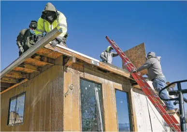  ?? PHOTOS BY MATT DAHLSEID/THE NEW MEXICAN ?? ABOVE: A crew with RoofCARE works on the Hernández home of Geraldine Lopez on Wednesday.
RIGHT: Lopez looks up at a leaky skylight that a crew with RoofCARE was working to replace.