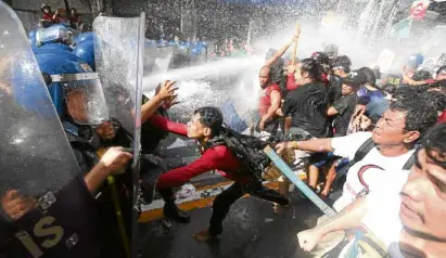  ?? —MARIANNE BERMUDEZ ?? DISPERSED Activists protesting the visit of US President Donald Trump to the country are dispersed by riot police using water cannons during a rally along UNAvenue in Manila.