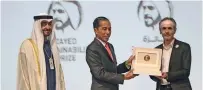  ??  ?? ENERGY FOR A CAUSE: Sheikh Mohamed bin Zayed looks on as Indonesian President Joko Widodo presents the award to Herve Gouyet from Electricia­ns Without Borders.