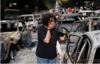  ?? FOTO: COSTAS BALTAS, REUTERS/NTB SCANPIX ?? En kvinne leter etter hunden sin blant utbrente biler i Mati i Hellas.