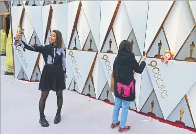  ?? MARK RALSTON / AGENCE FRANCE-PRESSE ?? People take photos in front of an Oscars themed backdrop on the red carpet on the eve of Sunday’s 90th Oscars ceremony, in Hollywood, California, on Saturday.