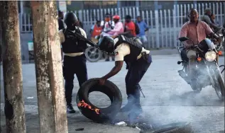  ?? Odelyn Joseph / Associated Press ?? Police work to remove road blocks set by anti-government protesters near a closed gas station amid fuel shortages in Port-au-Prince, Haiti, on Thursday. Haiti is struggling with a spike in gang-related kidnapping­s after President Jovenel Moïse was fatally shot at his residence on July 7 and a magnitude 7.2 earthquake killed more than 2,200 people in August.