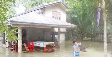  ??  ?? A resident gathers belongings from their flooded house after a tropical depression hit Loboc town, Bohol province, in the central Philippine­s. — AFP photo