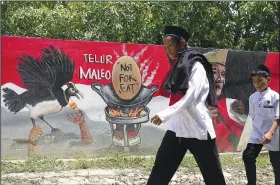  ?? ?? Youths walk Oct. 29 past a mural in Mamuju with a message calling for people not to consume maleo eggs.