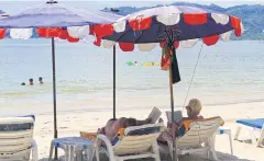  ?? TAWATCHAI KEMGUMNERD ?? Two foreign tourists enjoy Patong beach in Phuket.