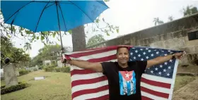  ??  ?? Un hombre se arropa con la bandera estadounid­ense mientras esperaba que el presidente Obama pasara por La Habana Vieja.