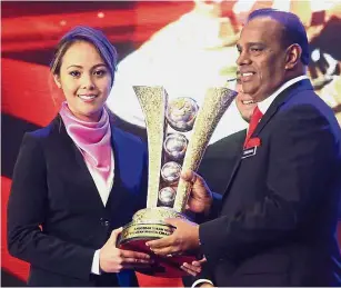  ?? — IZZRAFIQ ALIAS/ The Star ?? Well done: Syaidatul Afifah Badrul Hamidi (left) receiving the Women’s Team of the Year trophy from Deputy Youth and Sports Minister Datuk M. Saravanan on behalf of the women’s tenpin bowling team during the National Sports Awards in Kuala Lumpur on Tuesday.