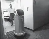  ?? MEL MELCON/LOS ANGELES TIMES ?? William Savoie of Burlington, Vt., opens the door for Wally, a robot bell boy, as it delivers his order of two bottled waters to his room at the Residence Inn by Marriott on Century Boulevard in Los Angeles.