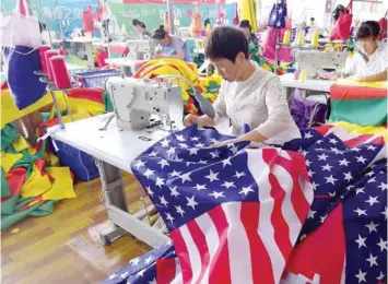  ?? — AFP ?? Chinese employees sew US flags at a factory in Fuyang in China’s eastern Anhui province.