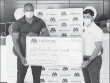  ??  ?? Marics and Company Ltd Inventory Controller Khemraj Jaikaran (at right) hands over the $1 million cheque to Deputy Director of the Civil Defence Commission Major Loring Benons at the company’s showroom on Friday