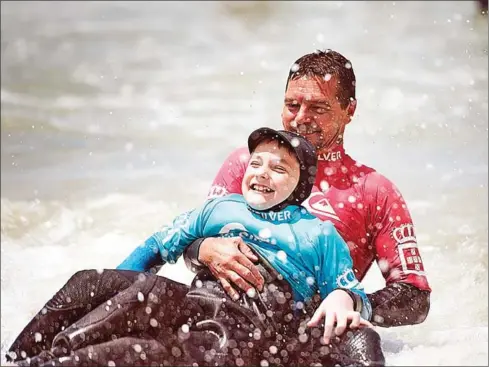  ?? RODGER BOSCH/AFP ?? JJ Booysens, 9, enjoys surfing with coach at an adaptive surfing event at Muizenberg beach in Cape Town last month.